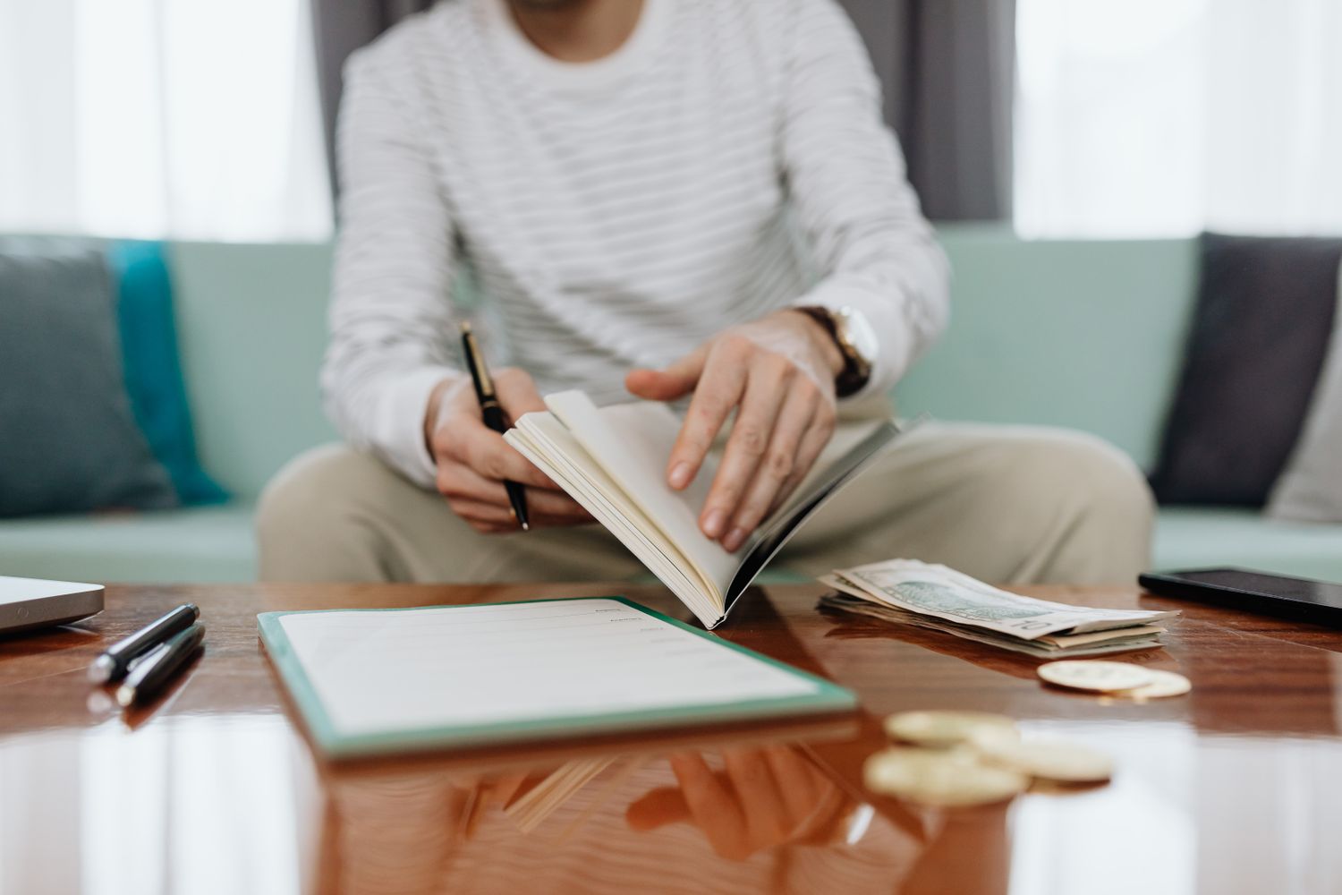 A person at home reviewing a budget notebook with cash on the table, representing the household planning needed before a UK fixed-rate mortgage deal ends and reverts to the standard variable rate