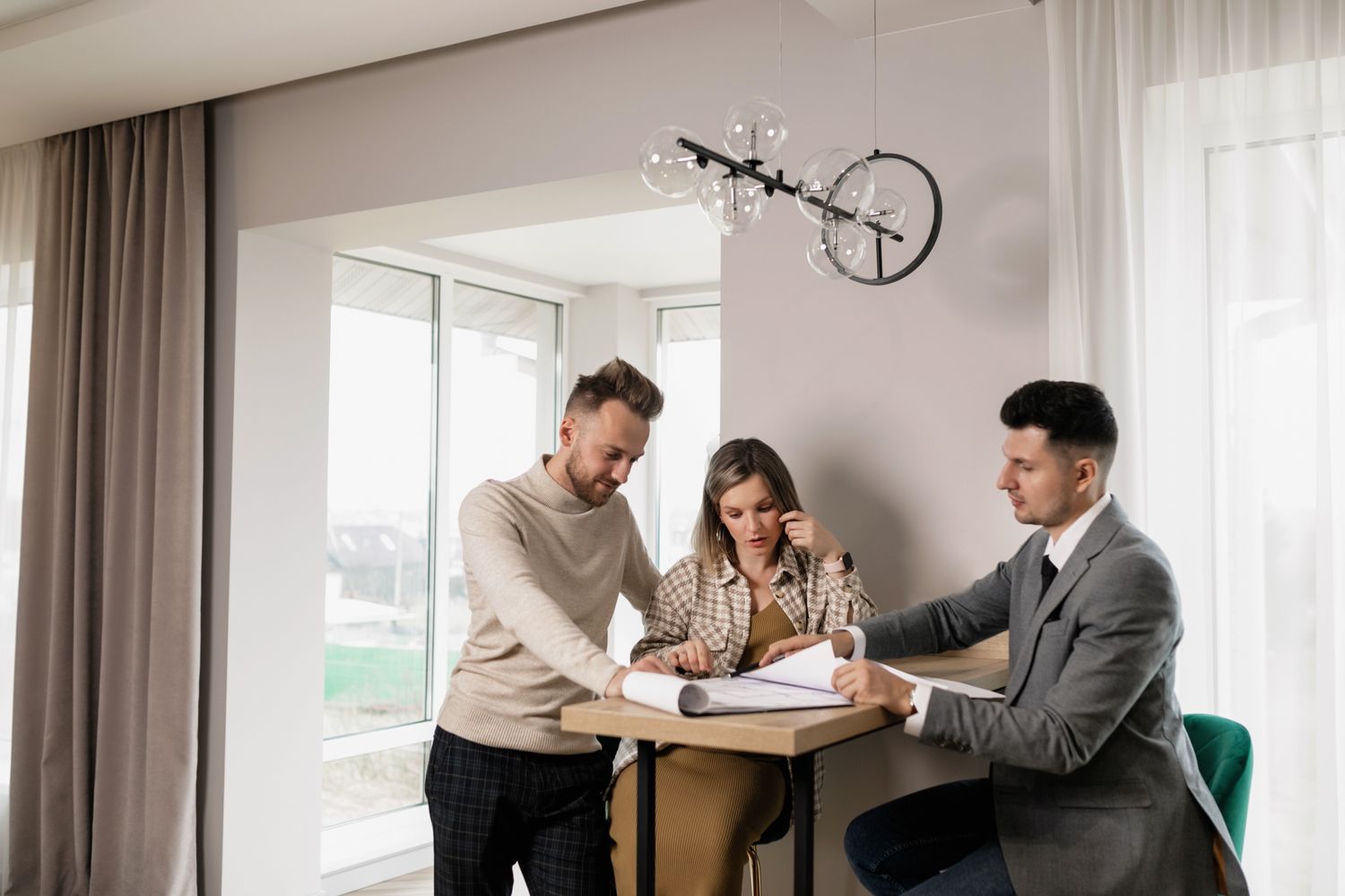 A couple reviewing paperwork with an advisor at a table, representing the point at which closing costs and final loan documents are reviewed before signing