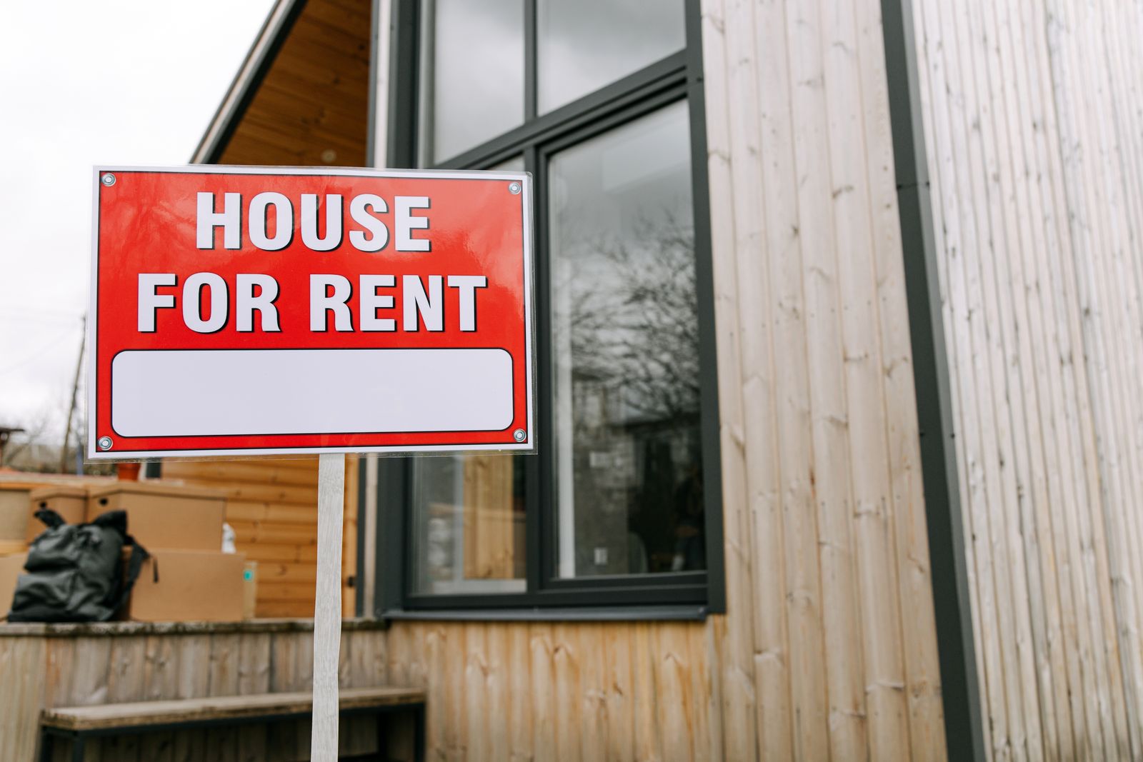 A red 'House for Rent' sign in front of a modern home, representing the point at which a landlord's rental yield calculation meets a lender's stress test for investment financing